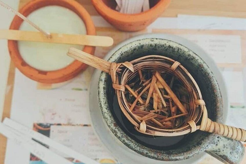 Una tazza di ceramica con coperchio di paglia intrecciata, un cucchiaio di legno e una piccola ciotola in terracotta con un altro cucchiaio di legno sullo sfondo. 3