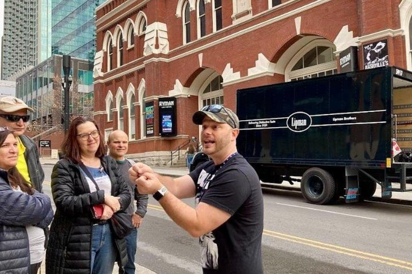 A street scene with a brick building, a black truck, and people standing on the sidewalk. 4