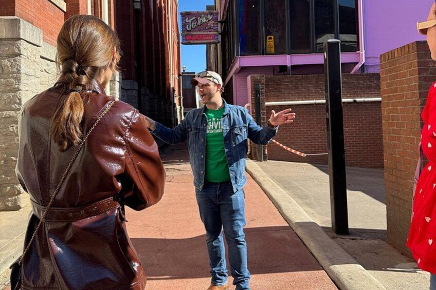 A street scene with a person gesturing, a building with a sign, and a brick wall. 3