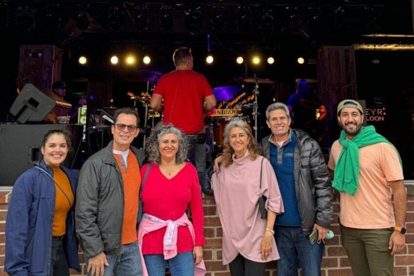 A group of people posing on a stage with musical instruments and a drum set in the background. 3