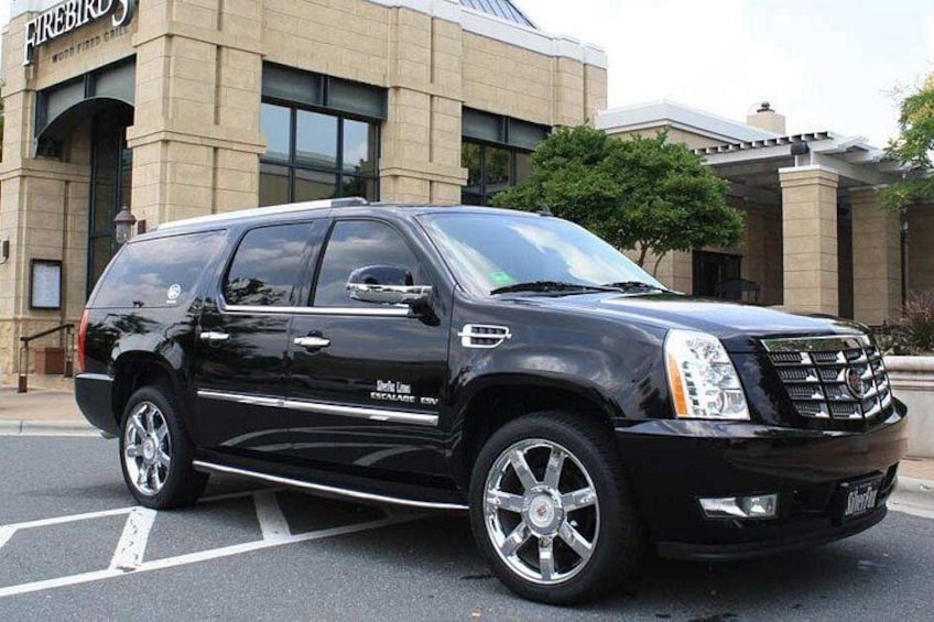 A black Cadillac Escalade SUV parked in front of a building with a sign that reads 'Firebird.' 2