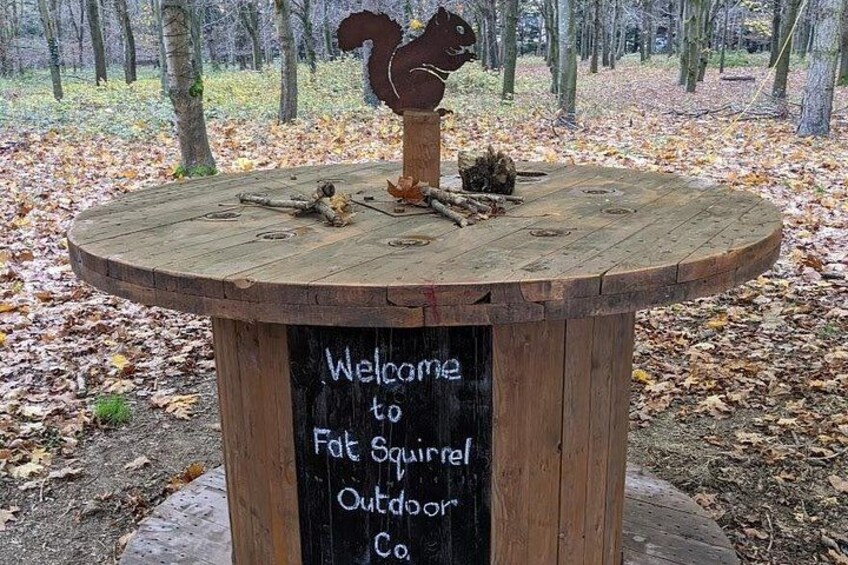 Et træskilt med en egernfigur og en velkomstbesked for Fat Squirrel Outdoor Co. 4