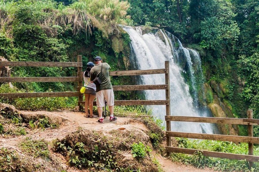 A waterfall, a wooden fence, and two people observing the scenery. 5