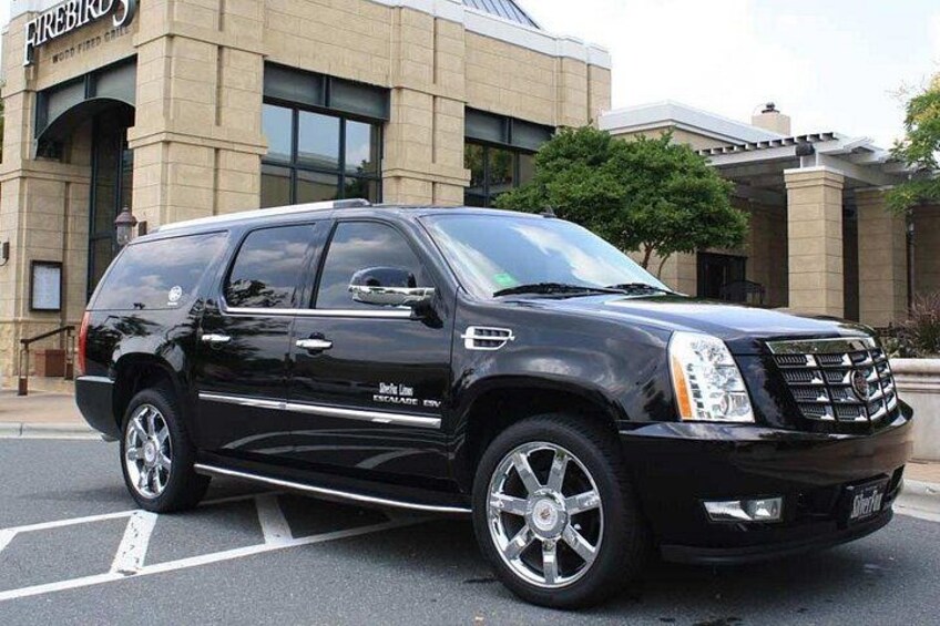 A black Cadillac Escalade SUV parked in front of a building with a sign that reads 'Firebird.' 4