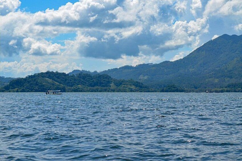 A lake with a boat, mountains in the background, and a partly cloudy sky. 3