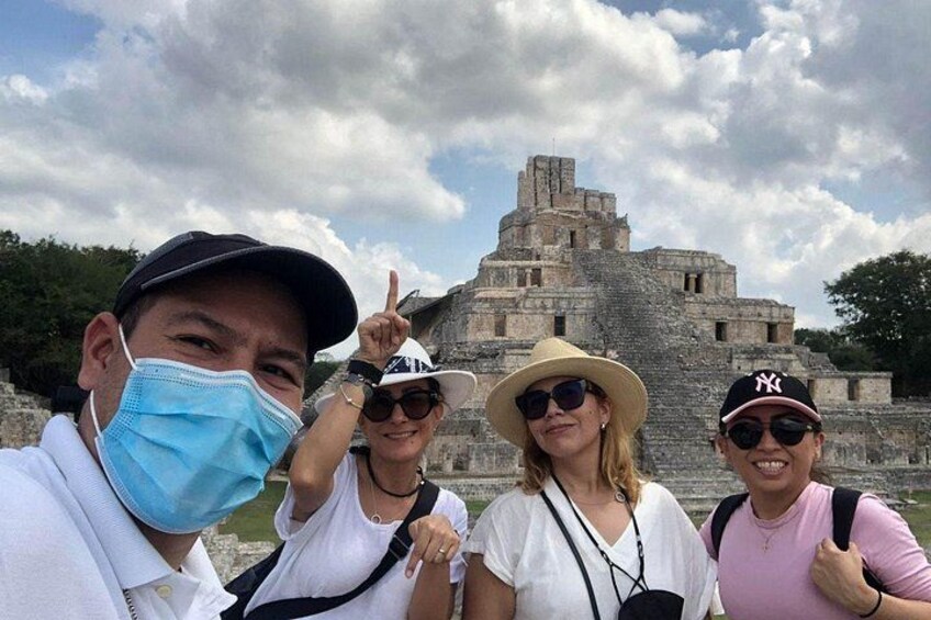 A group of people posing in front of a large ancient stone structure. 2