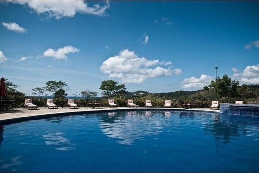 A swimming pool with lounge chairs and a clear blue sky. 2