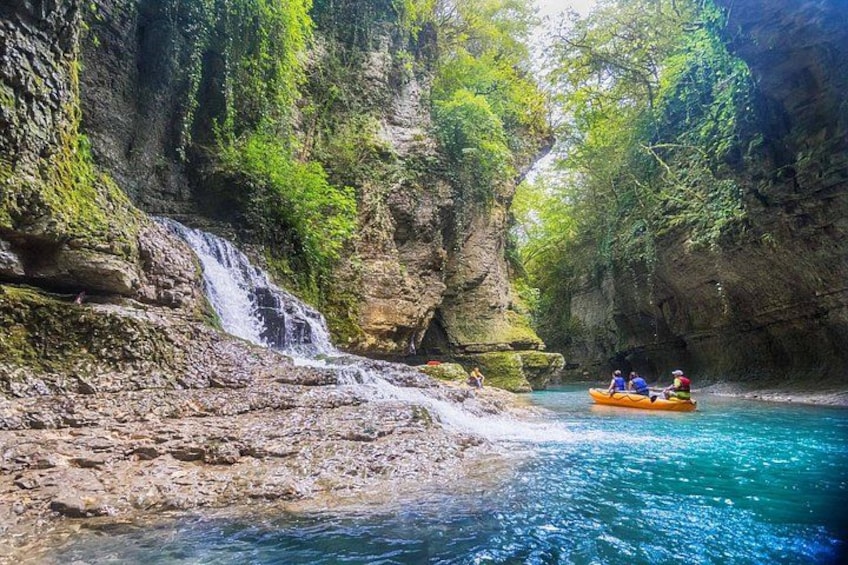 Une cascade, une rivière et un groupe de personnes pratiquant le rafting. 1