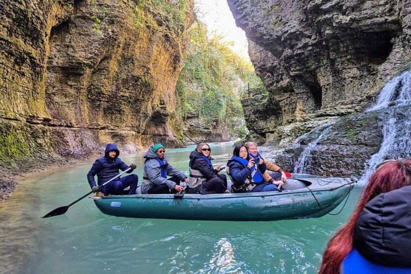 Un groupe de personnes se trouve dans un canoë vert sur une rivière, entouré de falaises rocheuses. 2