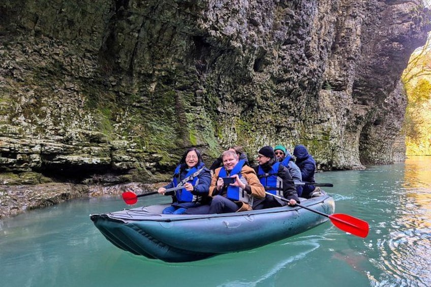 Un groupe de personnes se trouve dans un petit radeau gonflable sur une rivière paisible, entouré de falaises rocheuses. 3