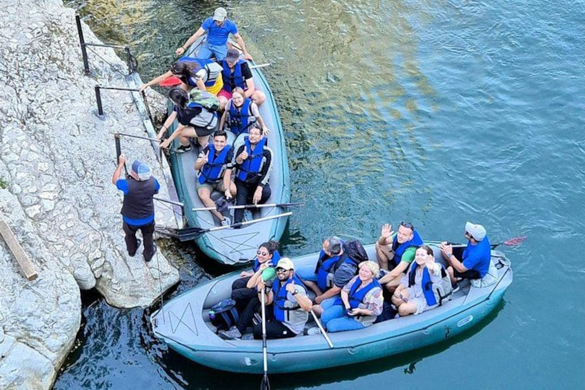 Deux bateaux pneumatiques sont amarrés sur une plage rocheuse, et des personnes se trouvent à l’intérieur. Une personne sur la plage aide l’un des bateaux à s’approcher du rivage. 4
