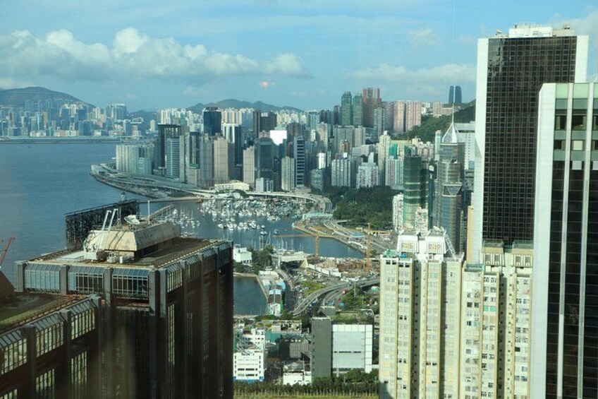A coastal cityscape with high-rise buildings, a marina, and a bridge. 2