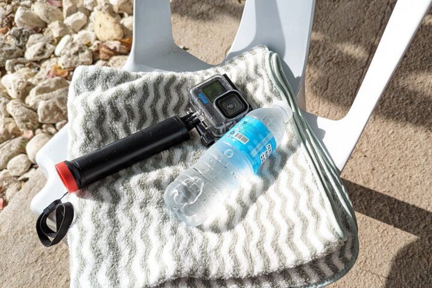 A GPS device, a water bottle, and a car key on a towel on a white chair. 2