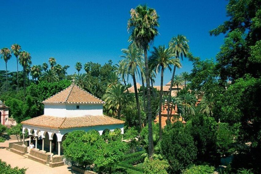 A gazebo with a tiled roof surrounded by lush greenery and palm trees. 2