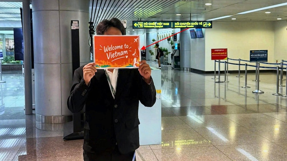 A person holding a sign that says 'Welcome to Vietnam' in an airport. 2