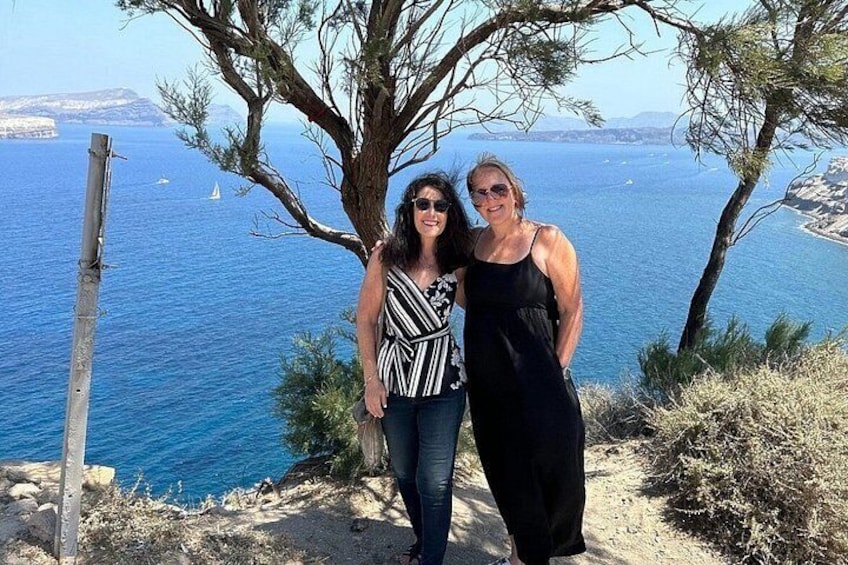 Two people standing by a tree overlooking a coastal view with the sea and distant land. 3
