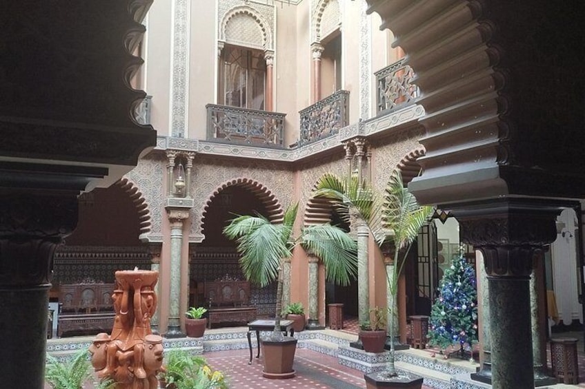 A courtyard with arches, potted plants, and a decorative fountain. 2