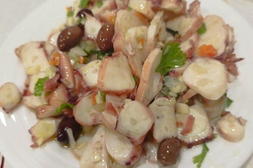 A plate of octopus salad with olives and herbs. 3