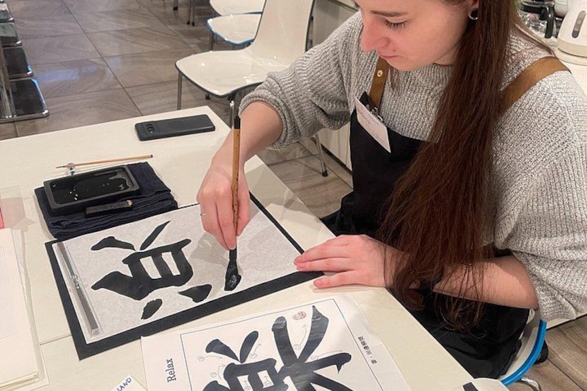 Iemand oefent kalligrafie met een penseel op papier. 5