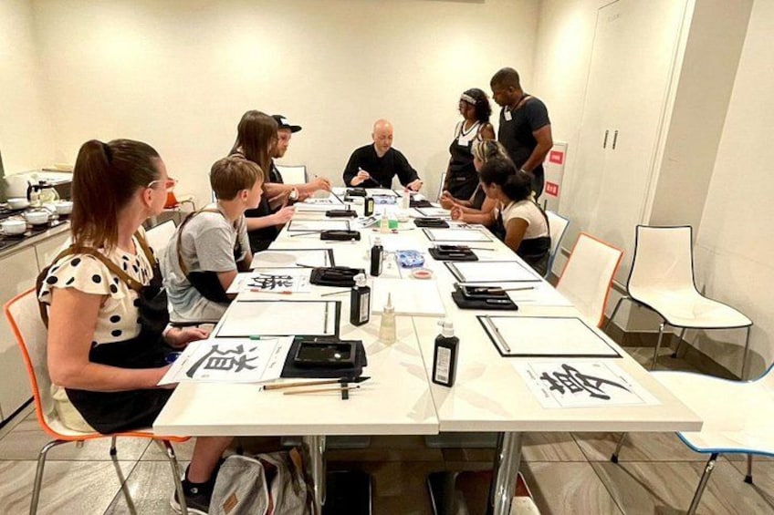 Een groep mensen zit rond een lange tafel in een vergaderruimte, met documenten en schrijfspullen op tafel. 3