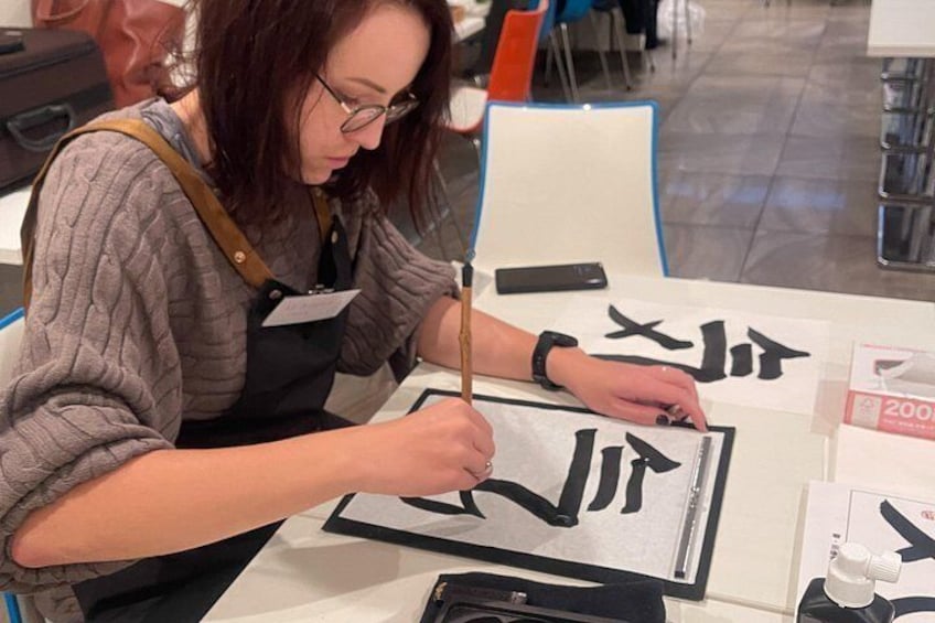 Une personne qui pratique la calligraphie sur une feuille de papier blanche. 3