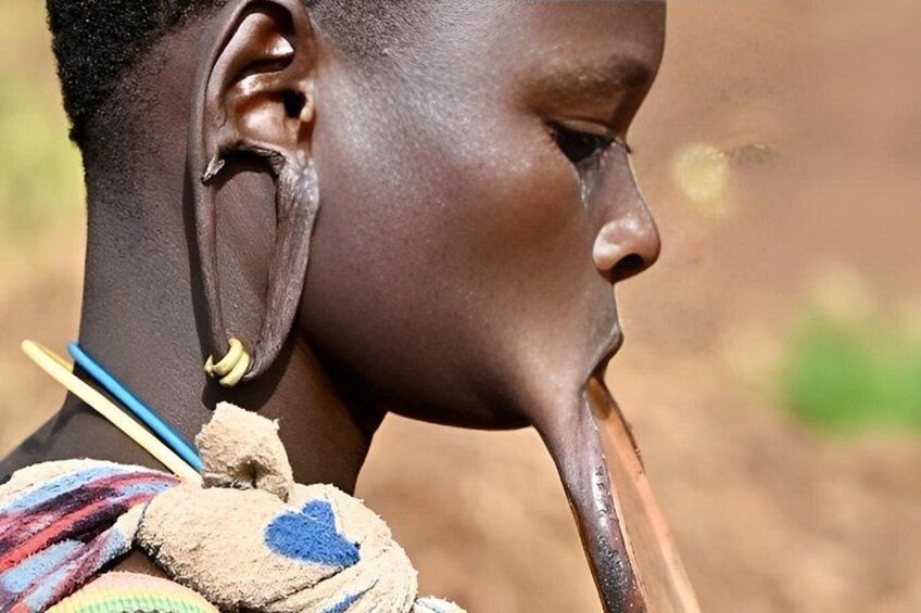 A person with a dark complexion, wearing a colorful beaded necklace and a dark garment. 5