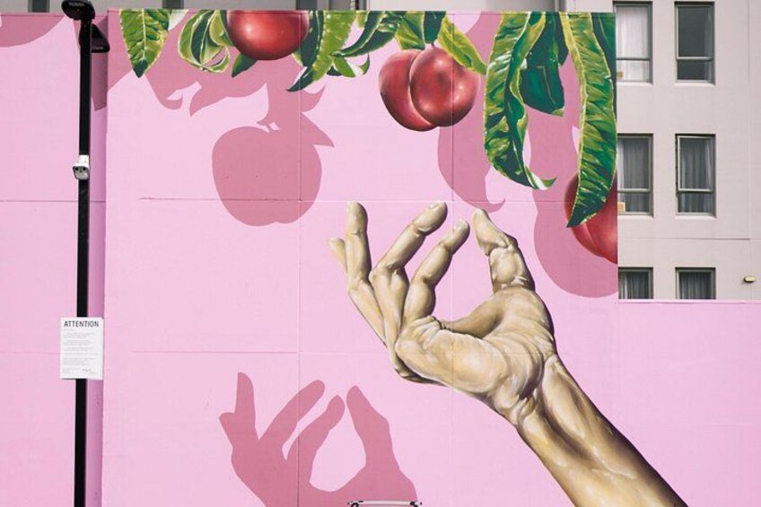 A pink wall with a large hand reaching for fruit. 3