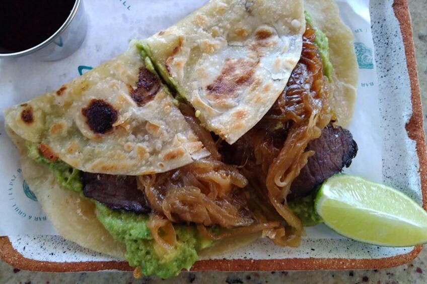 Quesadilla con carne, guacamole y una cuña de limón en un plato. 4