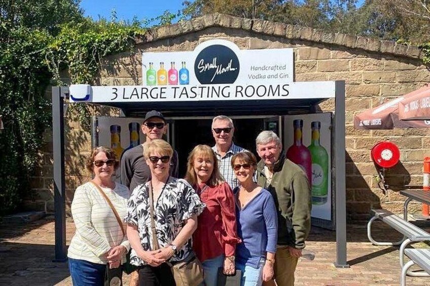 A group of people standing in front of a tasting room with a sign indicating 3 large tasting rooms. 2
