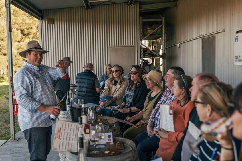 A group of people gathered around a table with bottles, possibly for a tasting or discussion. 3