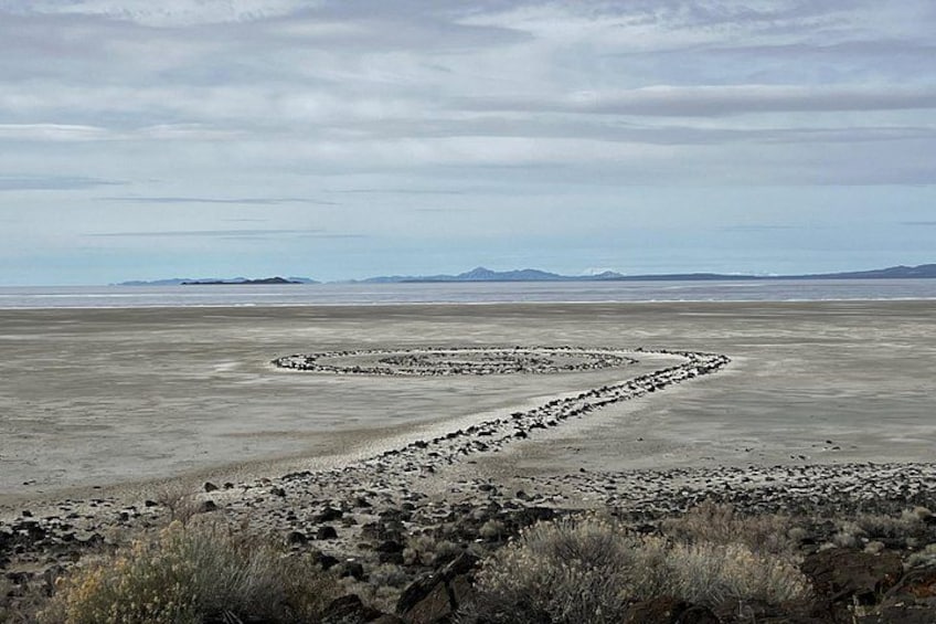 A vast, flat landscape with a distinctive spiral rock formation in the center. 5