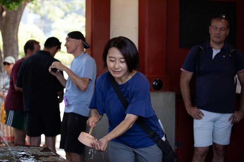 A person washing hands at a public water fountain. 4