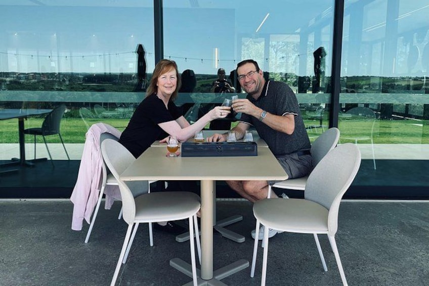 Two people sitting at a table with a laptop, a glass of drink, and a cup. 3