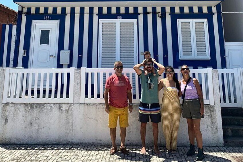 A group of people standing in front of a blue and white striped building with white railings. 3