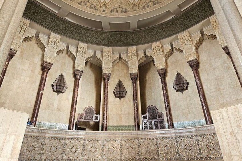 Un interior ornamentado con arcos y columnas detalladas, una alfombra con motivos y un techo abovedado. 5