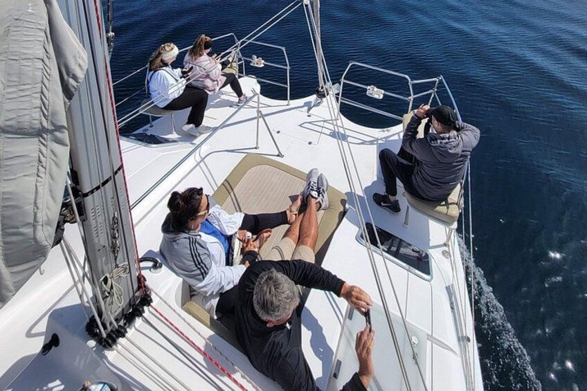 Un velero con gente en cubierta, una persona timoneando, y un mar en calma. 2