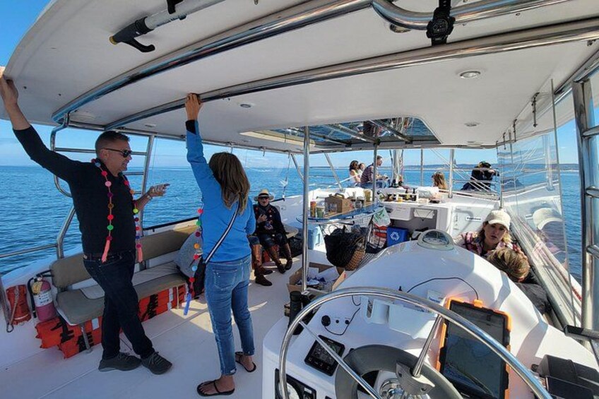 Un barco con gente en la cubierta, un timón y una persona levantando la mano. 3