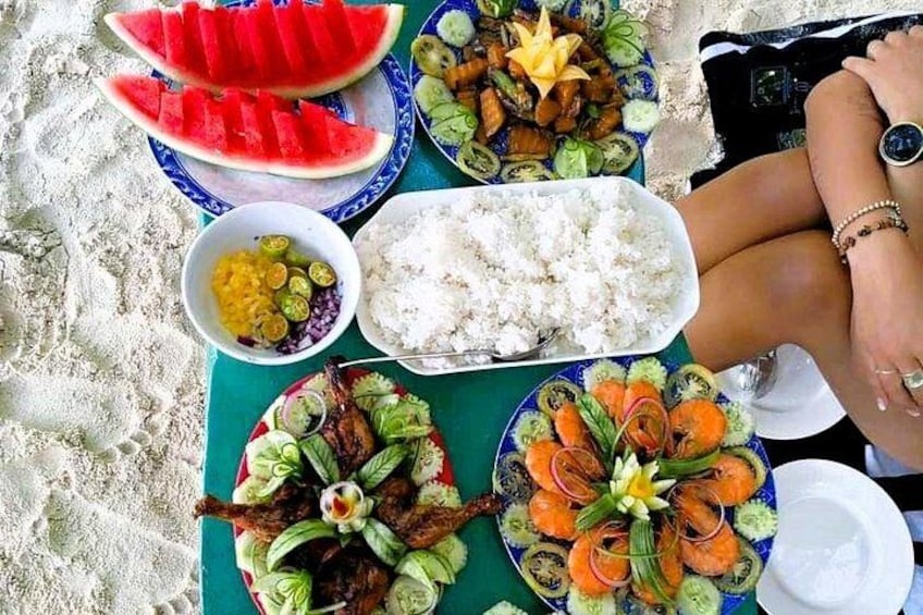 Una mesa con diversos platos, incluyendo sandía, arroz y una ensalada con verduras y carne. 5