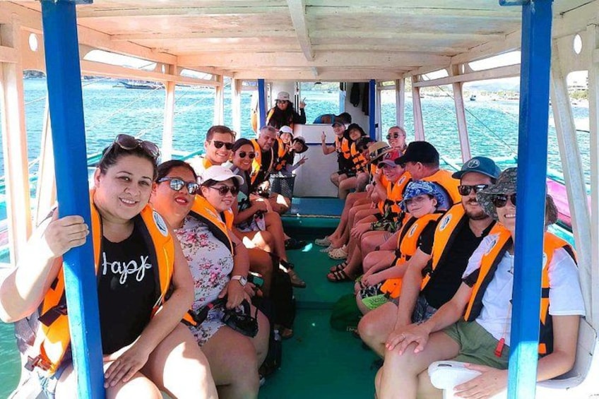 Un grupo de personas en un bote, con chalecos salvavidas y sentadas en filas. 3