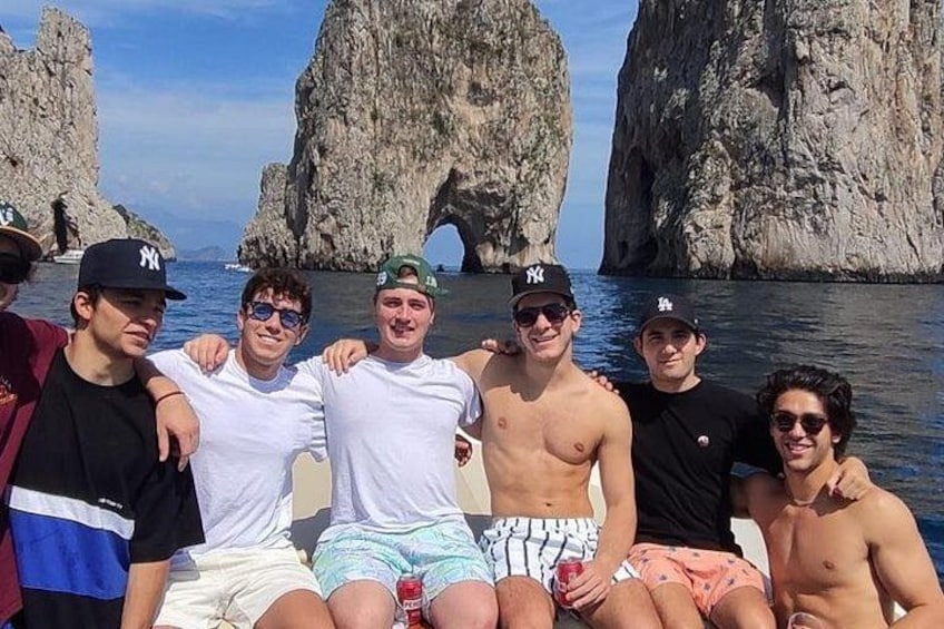 A group of people sitting on a boat near a rocky coastline with large rock formations. 2