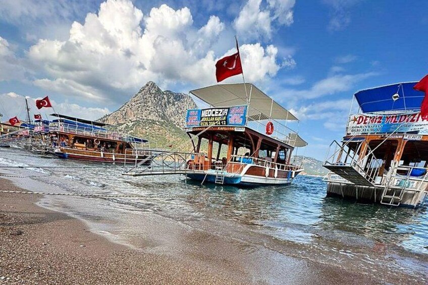 A beach with boats, a mountainous backdrop, and a clear sky. 3