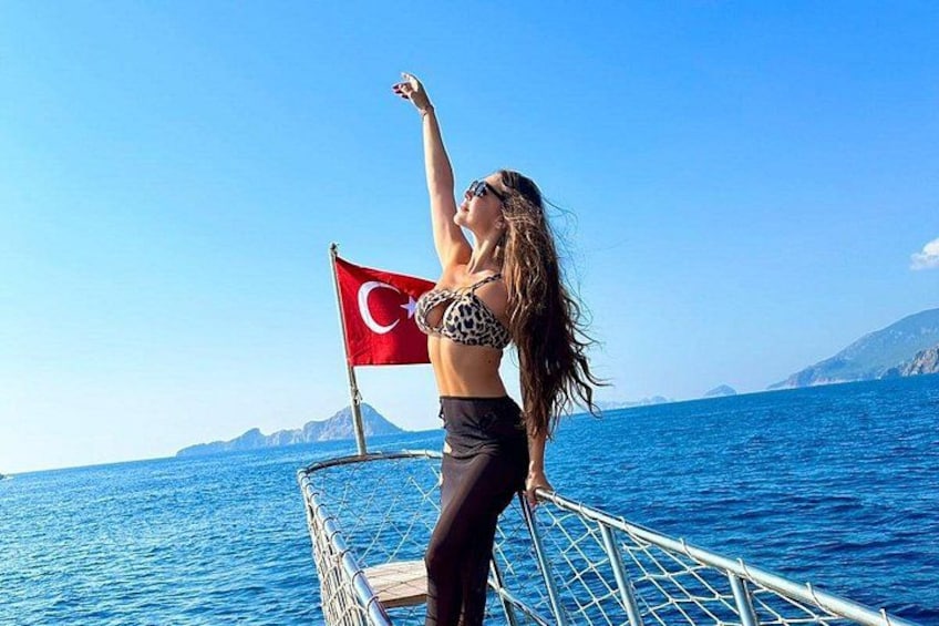 A person on a boat with a flag, water, and distant mountains. 2