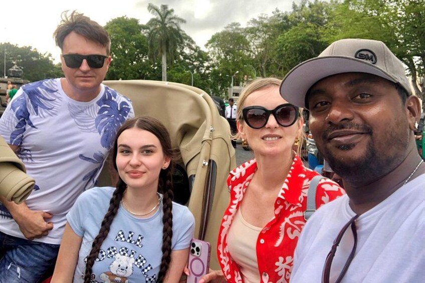 A group of people posing in a convertible car. 4