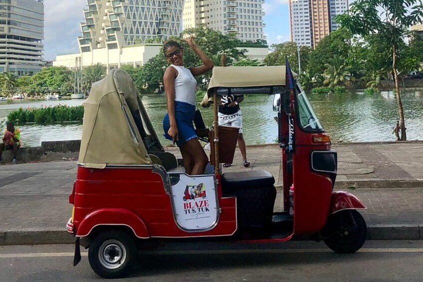 A red tuk-tuk with a beige canopy parked on a street. 2