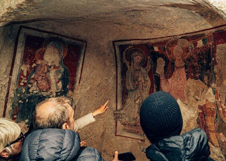 A group of people observing ancient frescoes in a cave. 4