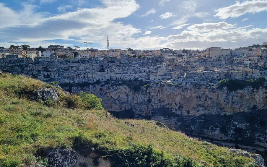 A densely packed hillside settlement with buildings, a rocky cliff, and a clear sky. 5