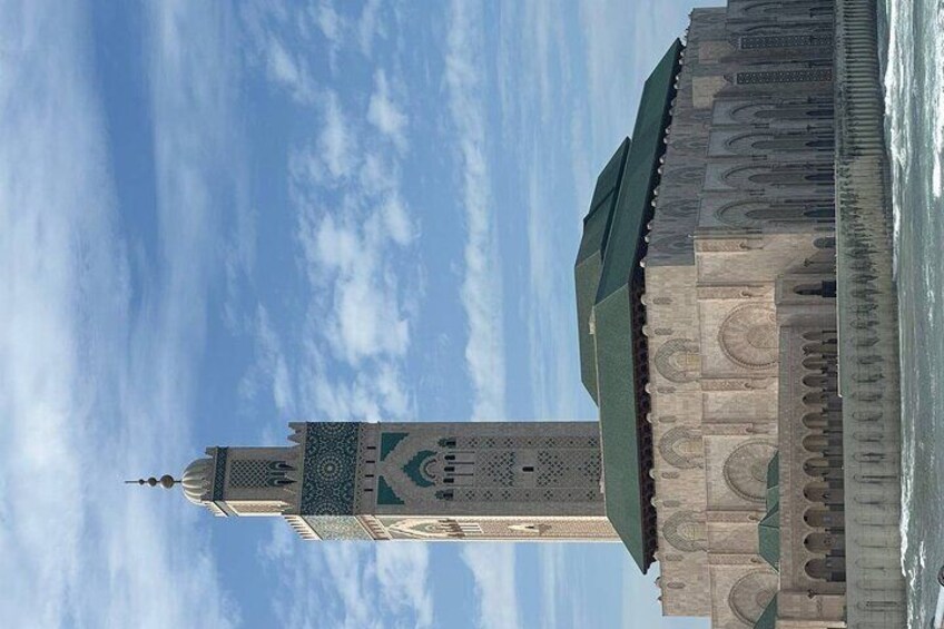 A tall minaret with intricate patterns and a green roof, set against a clear sky. 5