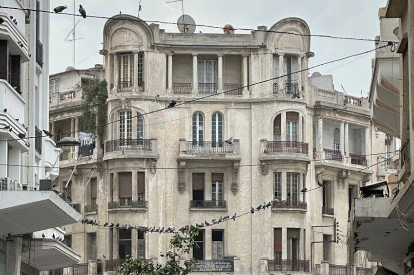 A multi-story building with balconies, a satellite dish, and a signboard. 3
