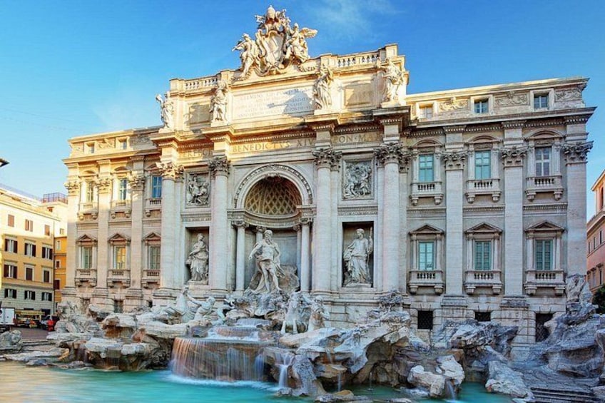 The Trevi Fountain with a large building in the background. 1