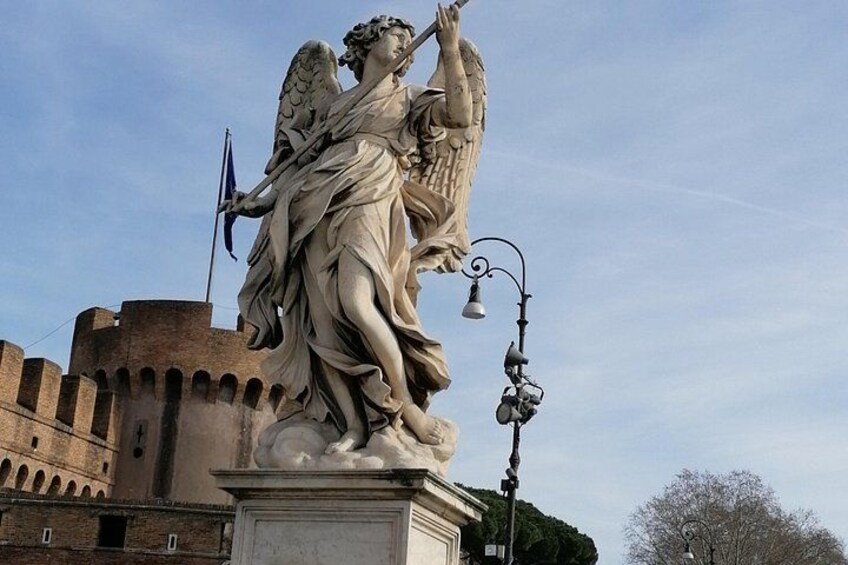 A statue of an angel with a trumpet, set against a historic building backdrop. 3